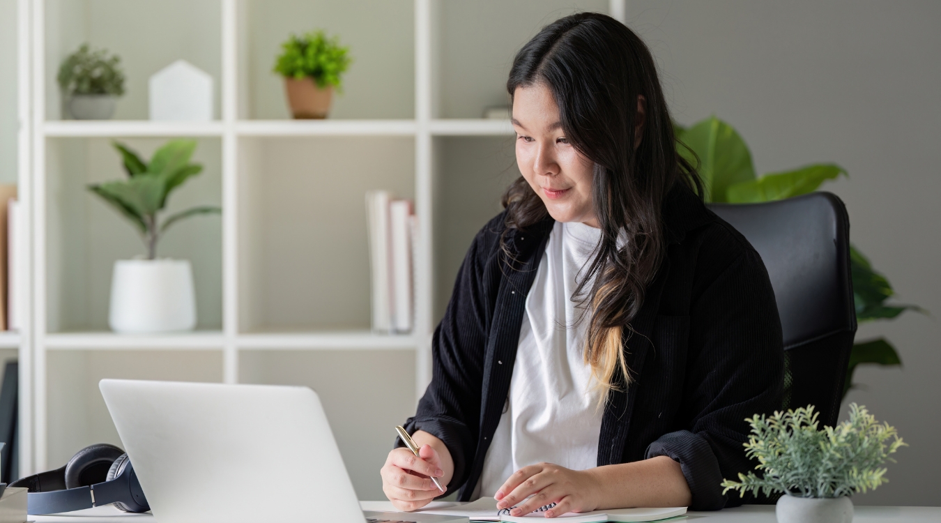 Aspiring Filipina freelancer taking notes on General VA course inside home office in casual outfit